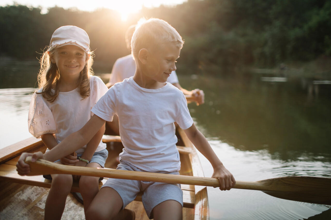 Brother,and,sister,paddling,canoe,on,sunset,lake