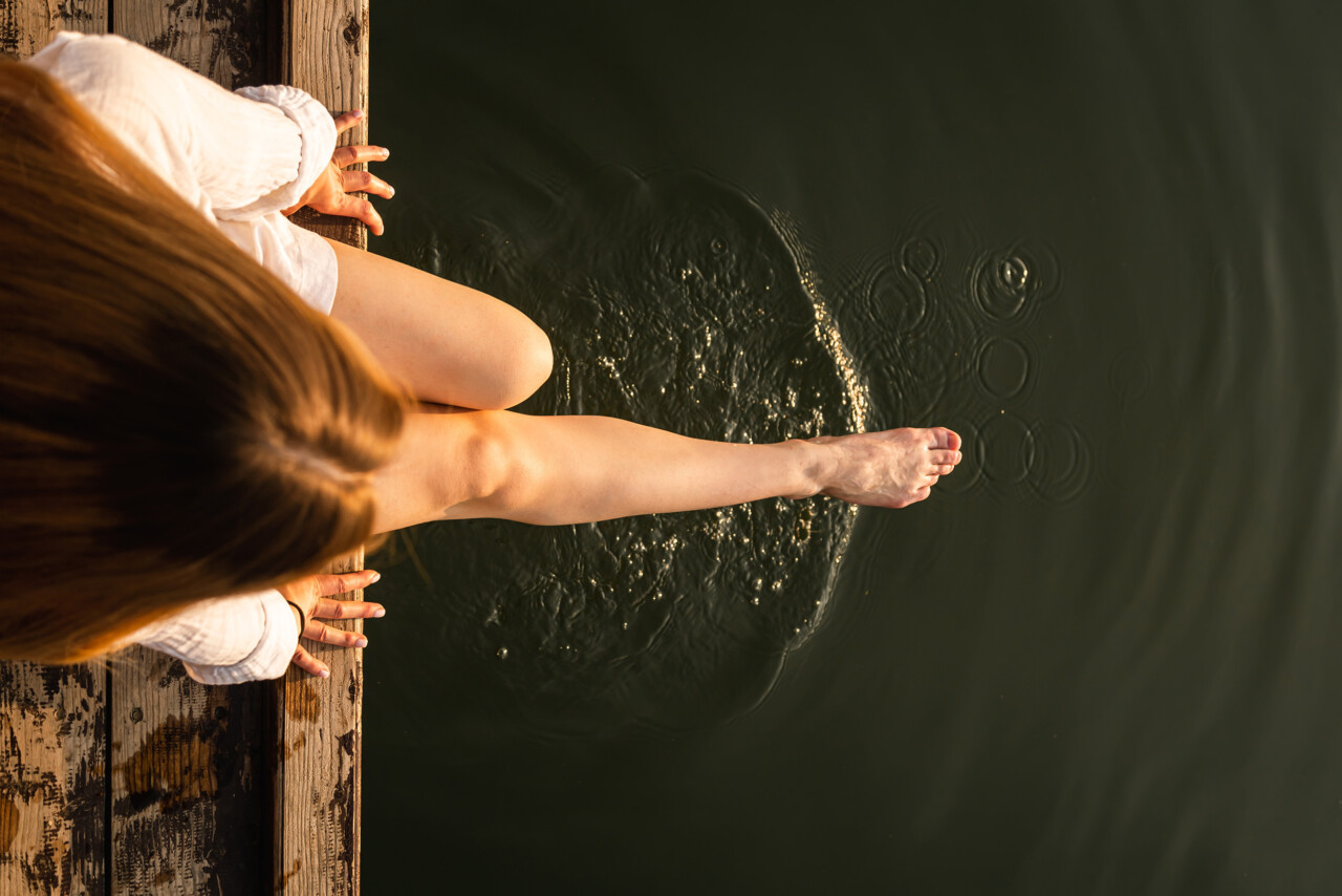 Woman,relaxes,by,the,lake,sitting,on,the,edge,of